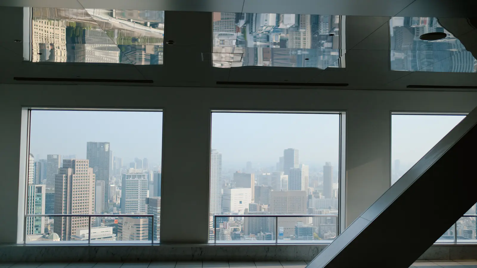 Empty upper-floor office interior looking out over a dense city through window bays