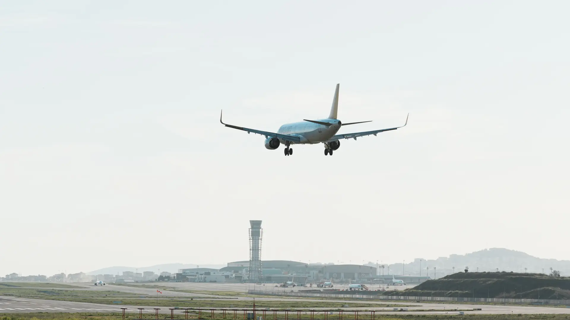 Airliner on final approach with landing gear down over an airport runway