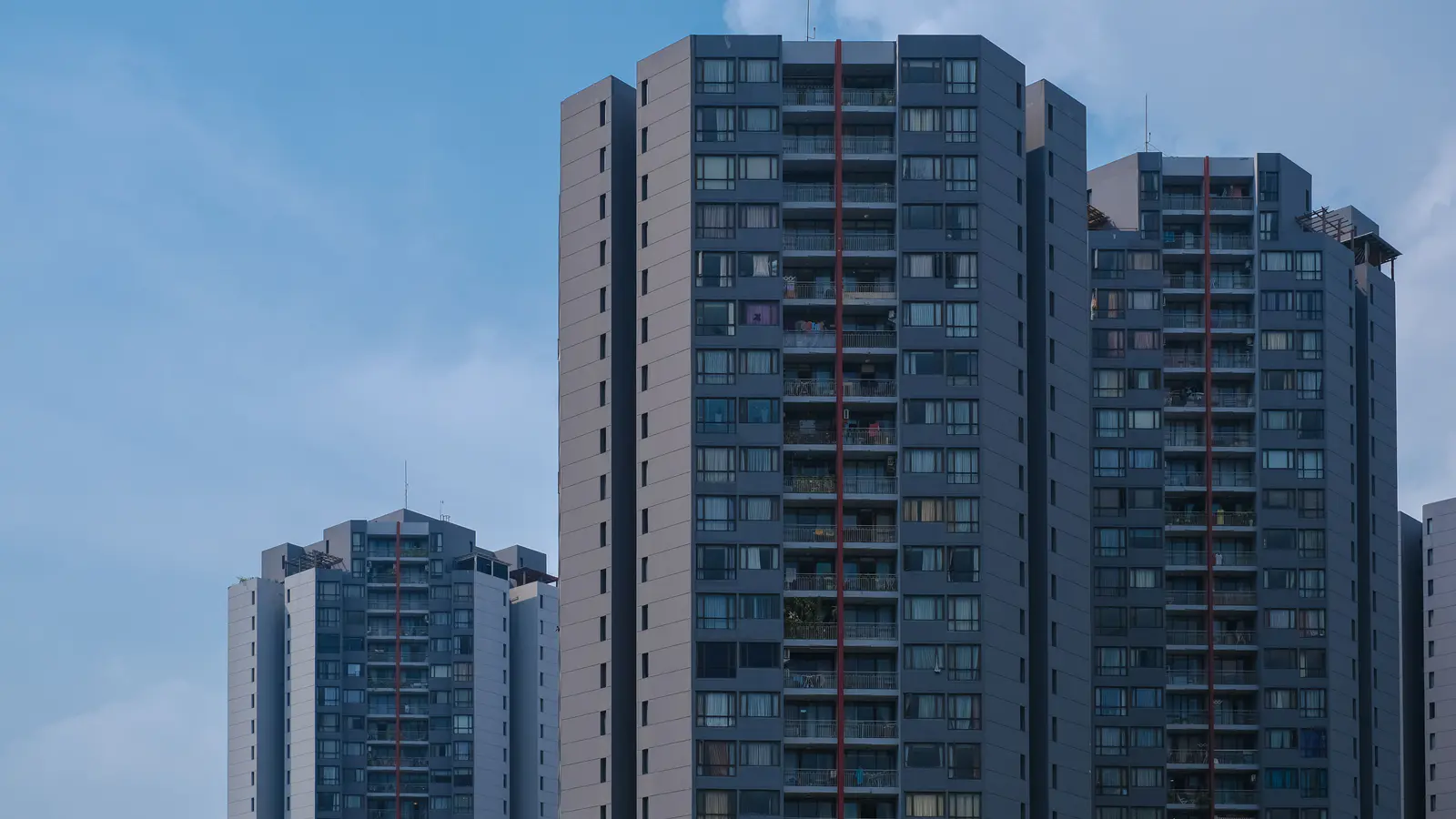 High-rise residential towers with balconies rising against a clear daytime sky