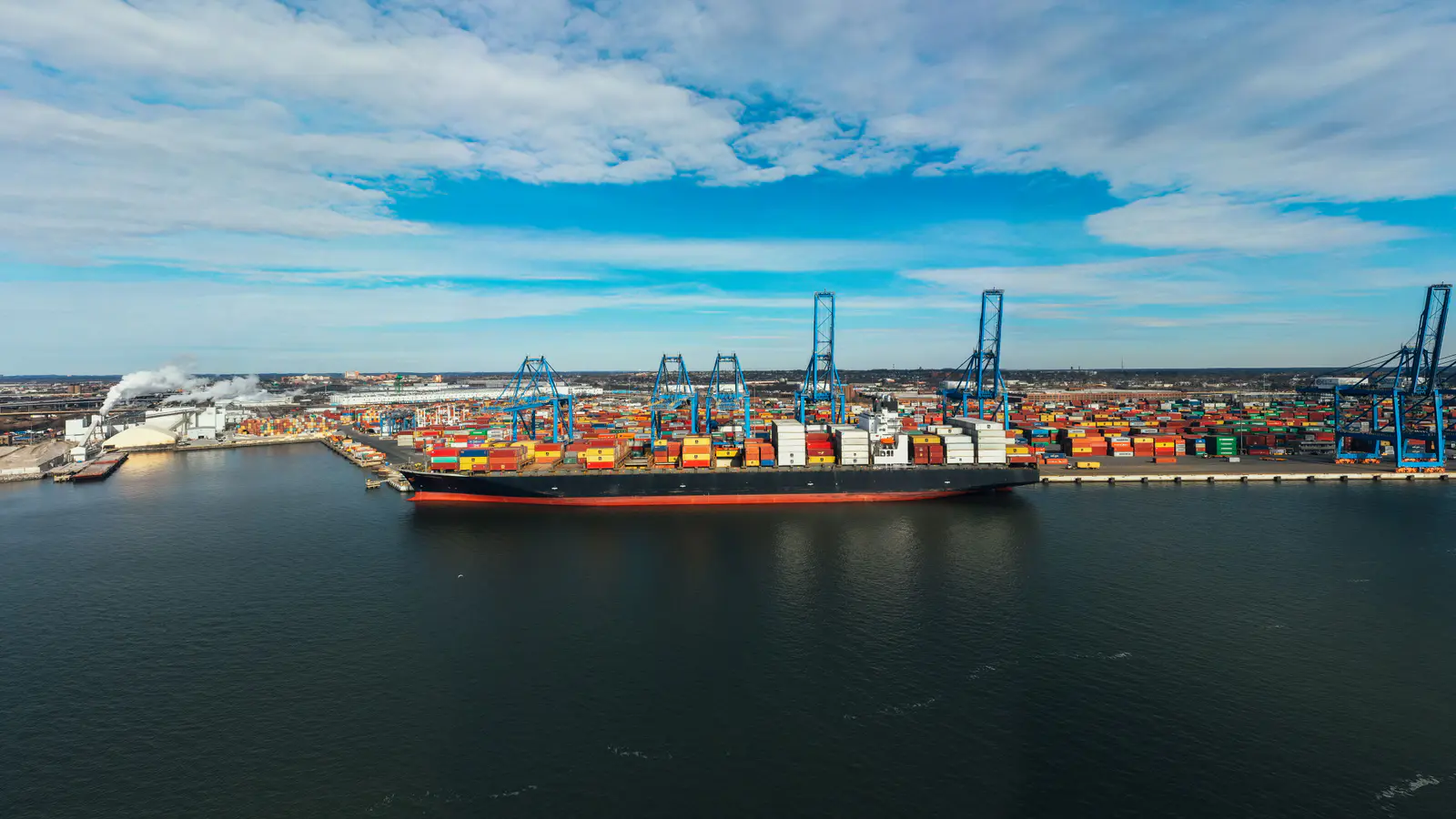Container terminal from the air with a berthed ship, gantry cranes and stacked boxes
